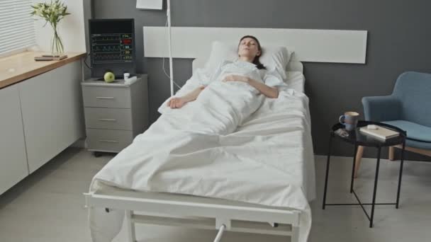 軽いきれいな医学区で昏睡状態にあるIv極に関連した病院のベッドで白人女性患者を長時間撮影した — ストック動画