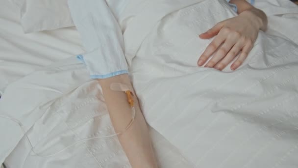 上のビューから病院のベッドに横たわっている認識できない白人女性の腕の上のカテーテルの中部 — ストック動画