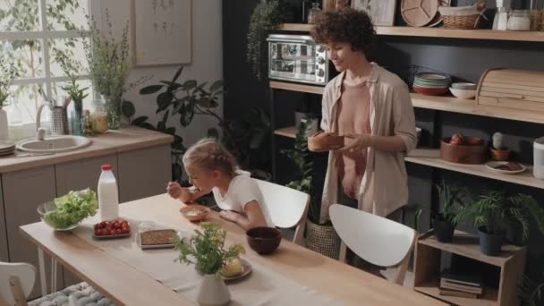 Preadolescente Chica Comiendo Desayuno Mientras Madre Poner Mesa Cocina Tiro — Vídeos de Stock
