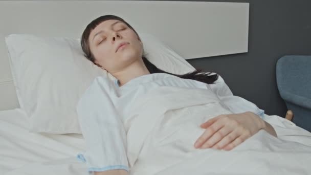 Ivの医学港および身に着けている脈拍の近くの病院のベッドで横たわっている昏睡状態の女性の患者の中型ショット — ストック動画