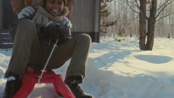 快乐的黑人男孩在阳光灿烂的冬日滑行 他快乐的父亲推着他 慢动作射门 — 图库视频影像