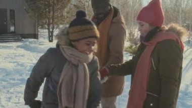 Farklı etnik çeşitlilikteki çiftler sıcak kıyafetler giyip kış günü el ele yürüyorlar, oğulları etrafta koşuşturup eğleniyorlar.