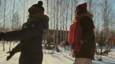 Orta Doğulu kadın ve siyah çocuk güneşli bir kış gününde dışarıda kartopu savaşı yapıyorlar.