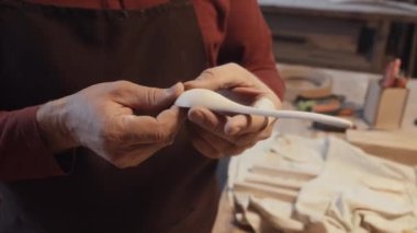 Seçici odaklanmış tahta kaşık vuruşu tanınmayan bir zanaatkarın ellerinde yaratılış düzgünlüğünü kontrol ediyor.