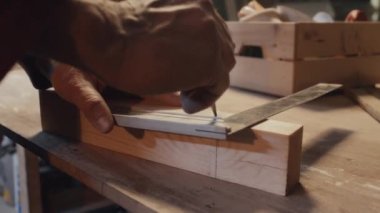 Beyaz adamın ellerinin, kalem ve cetvel kullanarak tahta parçasının uzunluğunu ölçen orta boy yakın çekimi.