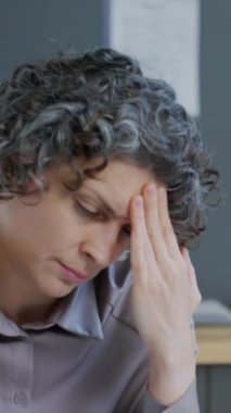 Dikey beyaz kadın hasta şiddetli baş ağrısı ve hastanede neden olduğu hakkında doktora şikayette bulunuyor.