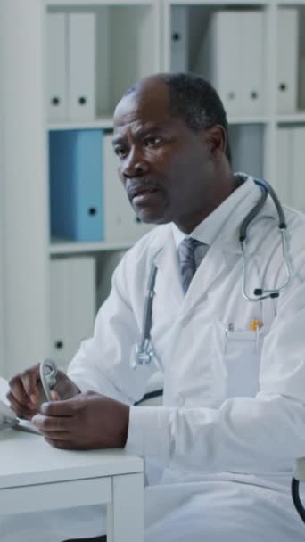 非洲裔美国医生在临床检查过程中使用Tonomometer检查病人血压的垂直照片 — 图库视频影像