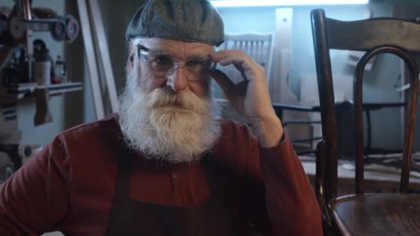Portret Starszego Białego Stolarza Opierającego Się Krześle Podczas Zdejmowania Okularów — Wideo stockowe