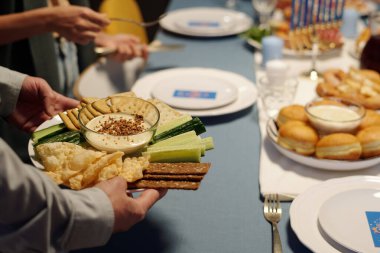 Taze salatalık, matzo, pide ekmeği ve yahudi bir adamın akşam yemeği için hazırladığı küçük cam kasede humus tabağına odaklan.
