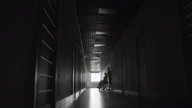 Hemşirelerin hastanede tekerlekli sandalye kullanıcılarına yardım ederken uzun monokromatik pozlar.