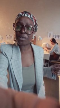 Gözlüklü Afrikalı Amerikalı kadın kreatif direktörün dikey POV UGC video blogu ve atölyedeki ork süreci hakkında konuşuyor