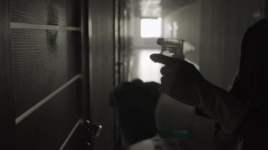 Uzun, karanlık koridordaki kiri temizlemek için sprey kullanan tanınmayan hademenin orta boy yakın çekimi.