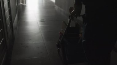 Otel koridorunda temizlik malzemeleriyle tramvayı iten tanınmayan hademenin diz boyu fotoğrafı.