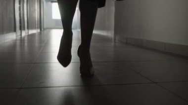 Kameraya doğru yürüyen tanınmayan kadın figürünün yüksek topuklu ayakkabılarıyla tek renkli fotoğraflarını çek.