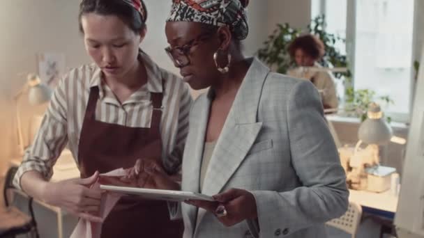非洲裔美国妇女工作室业主在指导缝纫车间人员的同时组织新服装系列制造过程的放大镜头 — 图库视频影像