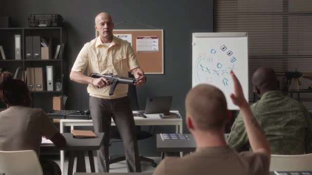 在军事学院的课堂上 与不同的学生和拿着来复枪的军事教官坐在一起回答关于霰弹枪使用的问题 — 图库视频影像