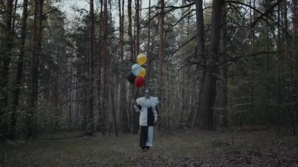Siyah Beyaz Elbiseli Bir Palyaço Karanlık Ormanda Renkli Balonlar Tutuyor — Stok video