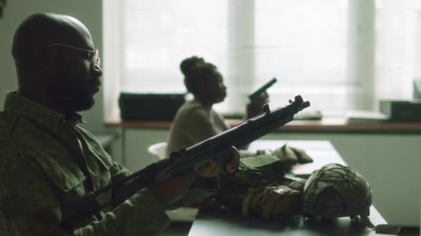 在军事院校学习如何使用机枪时 戴着眼镜和迷彩服的非洲裔美国男生侧胸向上看 — 图库视频影像