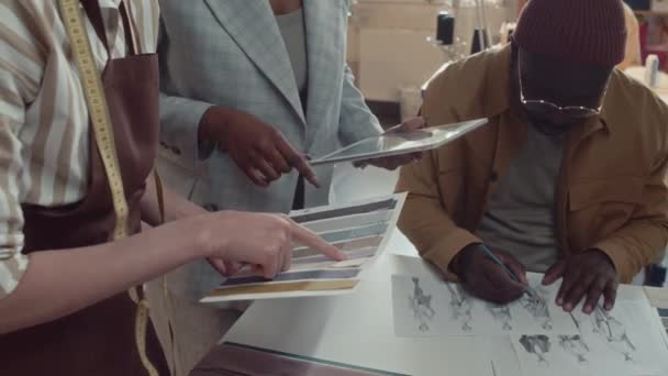 アトリエの同僚のサイドティルトショット 生地のサンプルを使用して新しい衣服のための色を選択し アトリエを調整するスケッチを描画するファッションデザイナー — ストック動画