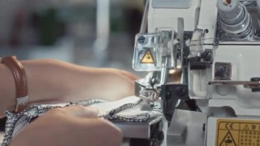 Tanımlanamayan terzilerin elleri kumaş parçalarına dikiş atan ve içeriden malzeme kesen dikiş makinesi kullanıyor.