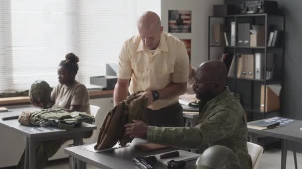 白人军事教官用板载体帮助非洲裔美国学员 然后在学院培训课上看着他组装手枪的侧拍 — 图库视频影像
