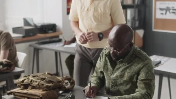 Askeri Eğitmenin Sınıfta Dolaşırken Öğrencilere Hizmet Akademisinde Yazılı Görevlerde Yardım — Stok video