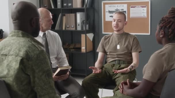 グループセラピー中に心理学者とアフリカ系アメリカ人の仲間の士官に彼の話を伝える白人青年兵士のアークショット — ストック動画