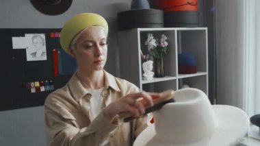 Beyaz şapkasını fırçalarken orta boy beyaz kadın tasarım.