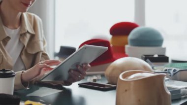 Şapka dükkanındaki tanınmayan beyaz kadının dijital tabletindeki fotoğraflara bakarken orta bölüm fotoğrafı.