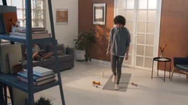 Oğlu dijital tablette video oyunları oynarken kıvırcık saçlı bir kadının yoga yapması.