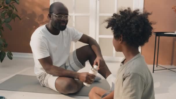 Africký Americký Otec Mluví Svým Synem Kudrnatými Vlasy Dává Láhev — Stock video
