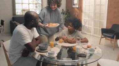 Beyaz bir anne yeni bir yemek getiriyor. Bu sırada Afrika kökenli Amerikalı kocası oğluyla masada oturuyor.