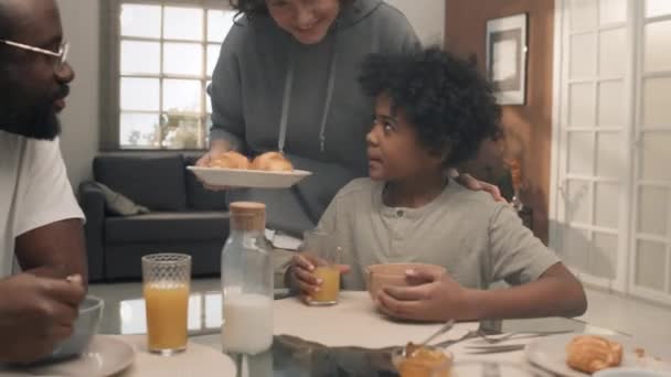 Mediana Toma Interracial Pareja Sentado Detrás Mesa Asegurándose Hijo Comiendo — Vídeo de stock