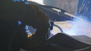 Ağır makine üretim tesisinde kaynak makinesi kullanan tanınmayan bir işçinin yakın çekim görüntüsü. Kaynak makinesi.