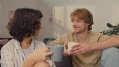 Genç ve mutlu bir çift, iyi aydınlatılmış bir odada oturmuş birbirleriyle konuşurken bir fincan sıcak kahve içiyorlar.