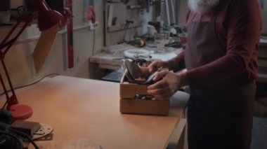 Atölyesinde çalışan ve zımpara kağıdından arta kalanlara bakan katılımcının yukarı doğru çekimleri.