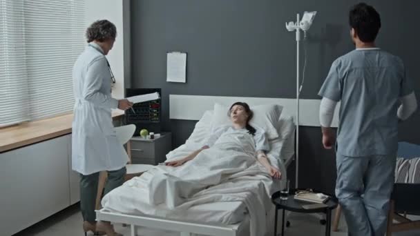 女性の医師と男性の看護師の長い3ショットが入って来て 患者の重要かつ状態をチェック — ストック動画
