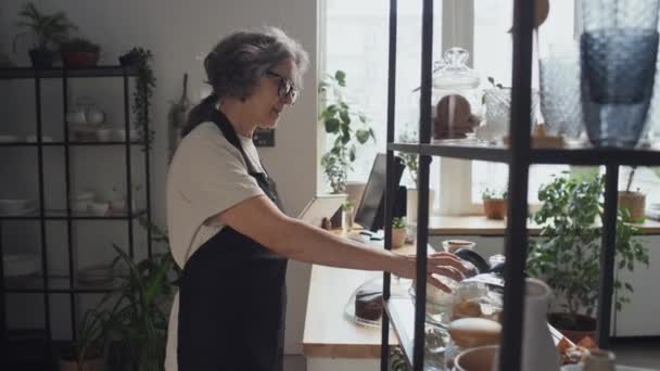 老年白种人咖啡店工作人员使用数码平板电脑检查产品和物品 — 图库视频影像