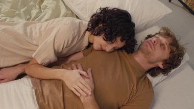 İki gencin birbirine çok yakın yattığı, yatakta birlikte uyuduğu bir fotoğraf.