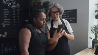 Kafkasyalı yaşlıların ve Afrikalı Amerikalı iş arkadaşlarının kafeteryada selfie çekerken orta boy bir fotoğrafı.