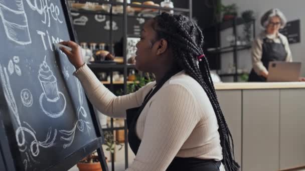 Medelhög Bild Svart Kvinnlig Kafé Arbetare Bär Förkläde Skriva Ombord — Stockvideo