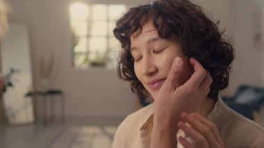 Siyah kıvırcık saçlı kız arkadaşının yüzünü dikkatle tutan tanınmayan bir adamın omuz üstü fotoğrafı.