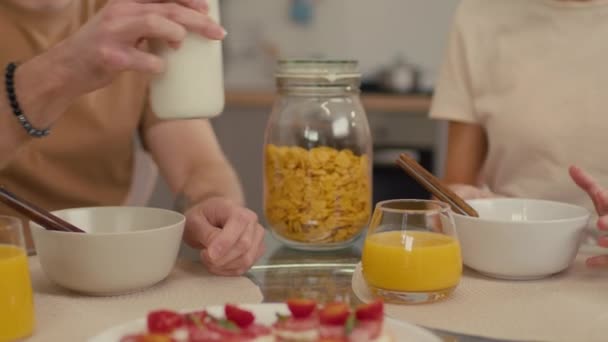 坐在厨房里吃含牛奶和橙汁的谷类食物的一对不认识的夫妇选择性地集中拍摄的照片 — 图库视频影像