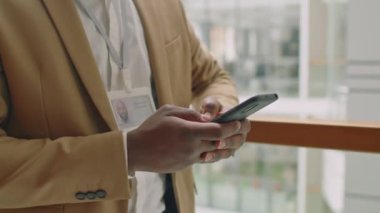 Tanımlanamayan siyah takım elbiseli bir adam koridorda duruyor ve akıllı telefonuna doğal ışık mesajı atıyor.