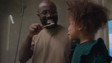 Baba ve kızı yatmadan önce diş fırçalamanın önemli hijyen kurallarını takip ederek eğleniyorlar.