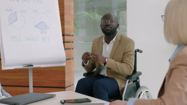 Афроамериканский Бизнесмен Инвалидной Коляске Делает Презентацию Коллегам Перед Доской Время — стоковое видео