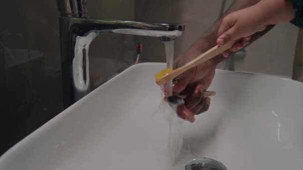 認識できないブラックマンと子供の手 トイレで歯ブラシを洗う シンク — ストック動画