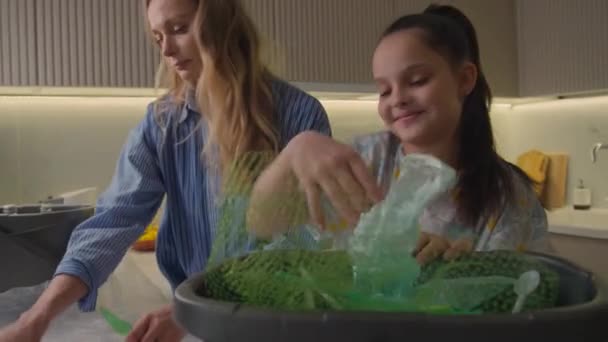 中镜头的少女和她的母亲把塑料垃圾扔进垃圾箱 — 图库视频影像