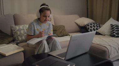 Laptop ve kulaklık gibi modern teknolojileri kullanarak okul derslerini okuyan genç bir öğrenci.