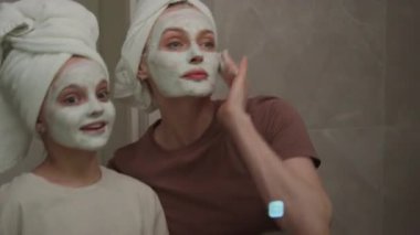 Krem maskeler ve banyo havluları giyerken anne ve kızın birbirlerine bağlanmalarının yansıması.